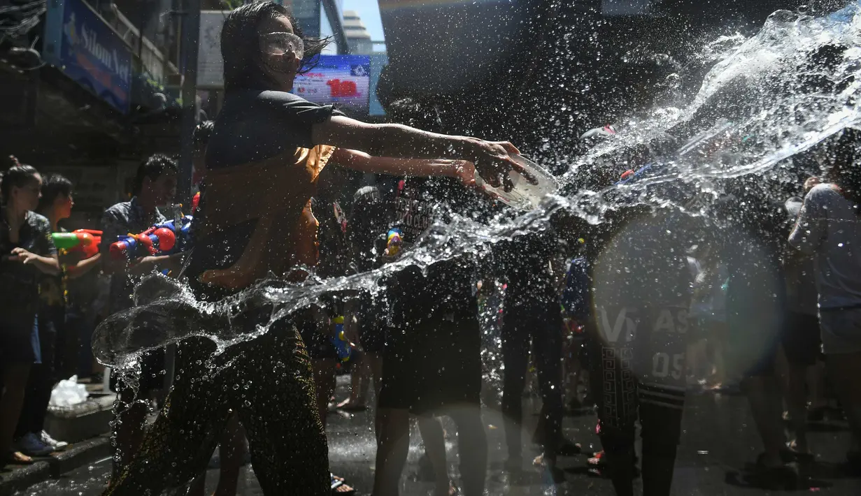 Orang-orang bersuka cita saling menyemprotkan air selama perama air dalam Festival Songkran di Silom Road, Bangkok, Jumat (13/4). Festival Songkran ini juga merupakan momen libur terpanjang di Thailand. (LILLIAN SUWANRUMPHA/AFP)