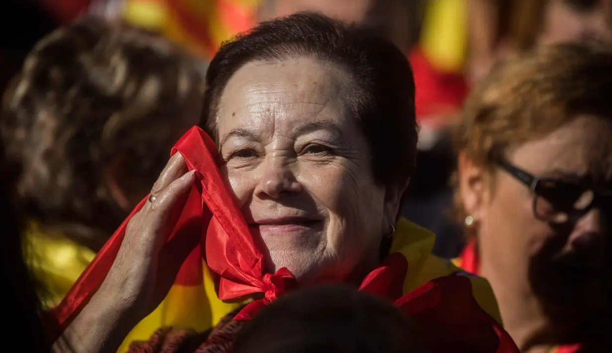 Seorang wanita membawa bendera Spanyol berpartisipasi dalam demonstrasi menentang deklarasi kemerdekaan Catalonia, di Barcelona, Spanyol, (29/10). Mereka menyerukan persatuan dan menolak deklarasi kemerdekaan Catalan. (AP Photo/Santi Palacios)