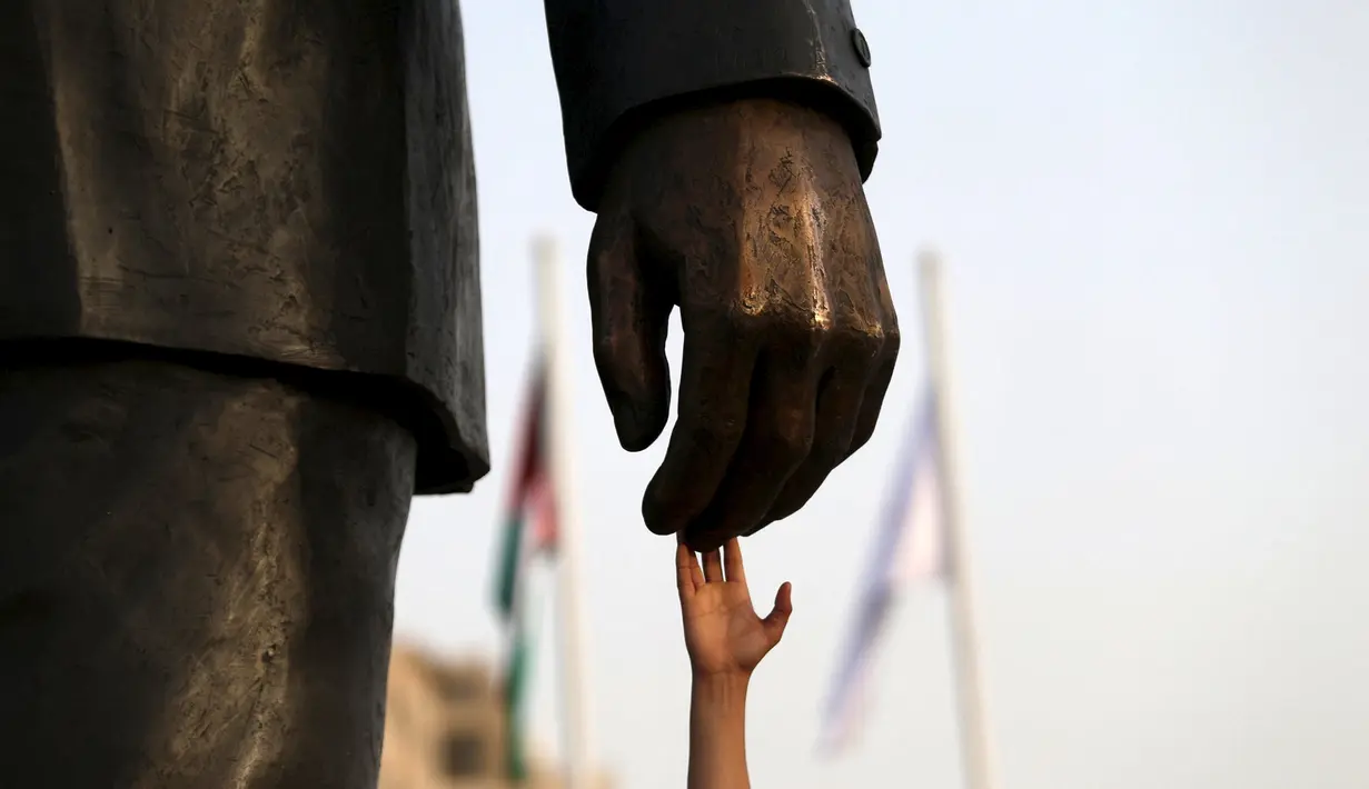 Seorang warga Palestina menyentuh patung Nelson Mandela saat peresmian di kota Ramallah, Tepi Barat, Selasa (26/4). Patung perunggu tersebut merupakan hadiah dari Johannesburg, ibukota Afrika Selatan, untuk bangsa Palestina. (REUTERS/Mohamad Torokman)