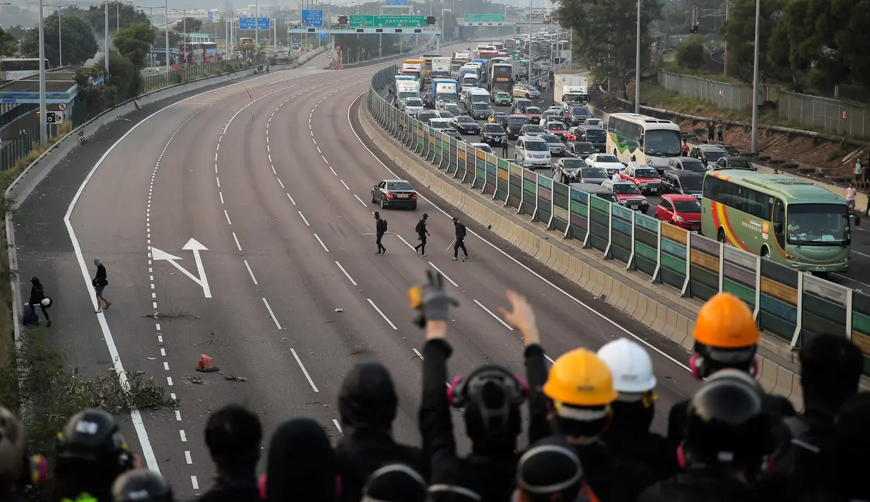 Demonstran prodemokrasi bersorak di jembatan ketika mereka memblokir jalan di luar Chinese University, Hong Kong, Rabu (13/11/2019). Gerakan antipemerintah Hong Kong yang telah berlangsung selama lima bulan bertindak semakin keras. (AP Photo/Kin Cheung)