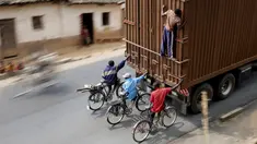 Para Pengendara sepeda menumpang di belakang sebuah truk di luar ibukota Bujumbura, Burundi, (19/7/2015). Untuk menjual pisang Setiap hari puluhan pengendara sepeda dari Bugarama menuruni jalanan bukit sepanjang 45 kilometer. (REUTERS/Mike Hutchings)