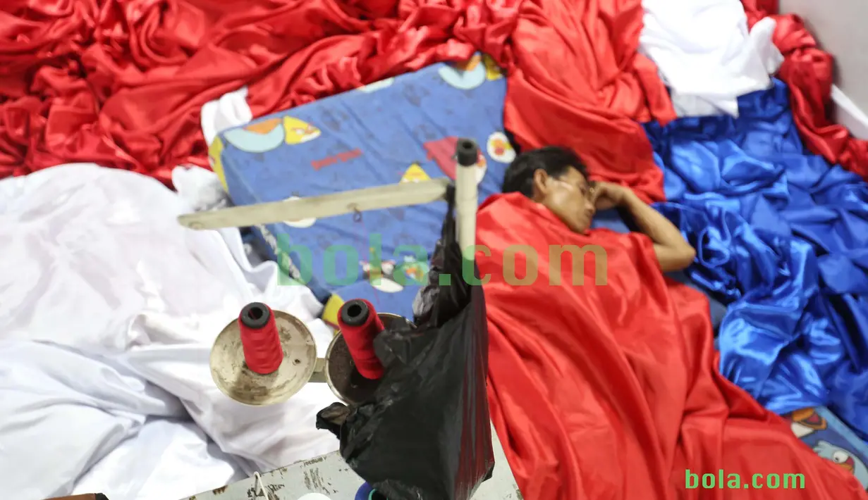 Suporter tertidur usai ikut dalam kegiatan menjahit bendera Merah-Putih raksasa di Tangerang, Sabtu (31/10/2015). Selain ingin mencatat rekor dunia, tema dasar adalah "One Soul, One Nation Untuk Sepakbola Indonesia".  (Bola.com / Nicklas Hanoatubun)
