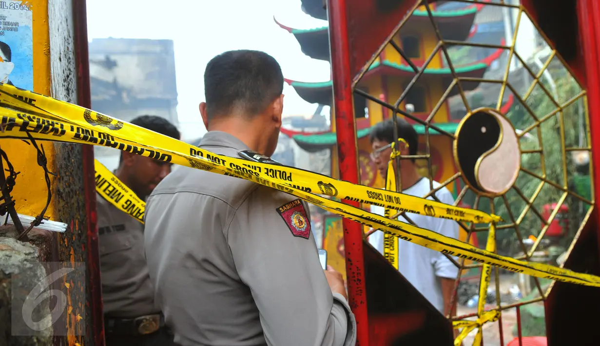 Petugas kepolisian saat menjaga lokasi Vihara Butong, Tangerang, Banten, Jumat (19/2). Dinas Pemadam Kebakaran mengerahkan 13 mobil pemadam kebakaran dan 70 personel untuk memadamkan api yang membakar vihara. (Liputan6.com/Faisal R Syam)