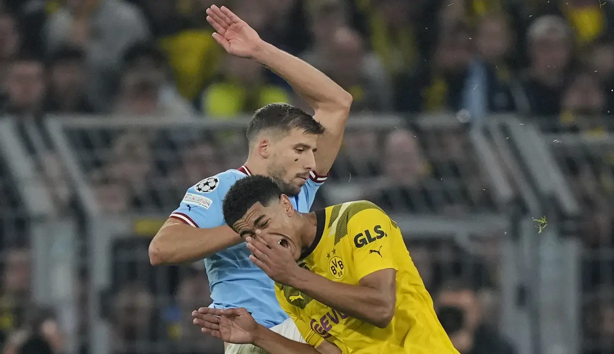 Gelandang Borussia Dortmund Jude Bellingham meringis kesakitan setelah berbenturan dengan bek Manchester City Ruben Dias pada matchday 5 Grup G Liga Champions 2022/2023 di Signal Iduna Park, Rabu (26/10/2022) dini hari WIB. Borussia Dortmund menahan imbang Manchester City dengan skor tanpa gol. (AP Photo/Martin Meissner)
