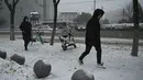 Orang-orang berjalan melintas di jalan saat salju turun di Beijing, China, Minggu (7/11/2021). Badai salju awal musim telah menyelimuti sebagian besar Cina utara termasuk ibu kota Beijing, mendorong penutupan jalan dan pembatalan penerbangan. (Noel Celis / AFP)