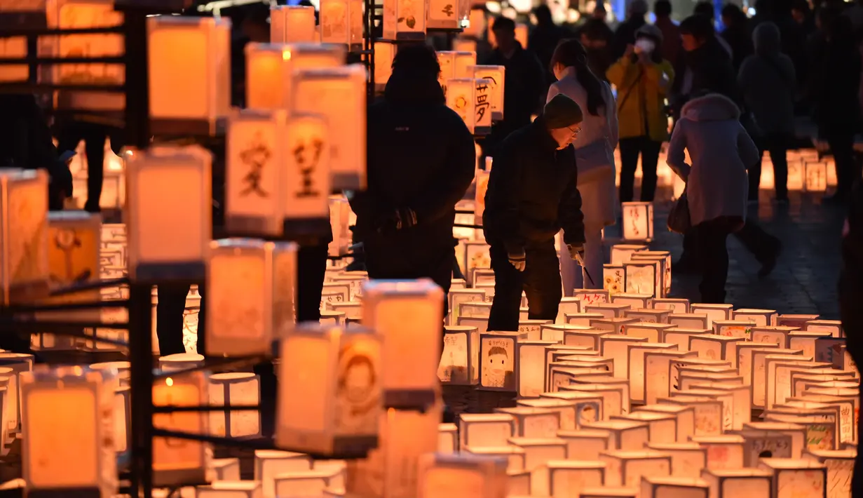 Pengunjung melihat lentera kertas saat memperingati bencana gempa tsunami di Natori, Prefektur Miyagi, Jepang (11/3). Masyarakat Jepang memperingati enam tahun gempa dan tsunami yang terjadi pada 2011 lalu. (AFP/Kazuhiro Nogi)