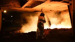 Seorang pekerja mengenakan pakaian pelindung membuat baja di Salzgitter, Jerman (22/3). Di pabrik ini, pasir besi bisa diolah menjadi baja dengan lapisan yang kuat. (AP Photo / Markus Schreiber)