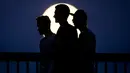 Tiga pria berjalan melintasi jembatan Ignatz Bubis saat tampak bulan purnama di Frankfurt am Main, Jerman barat,(10/5). (AFP Photo/dpa/Frank Rumpenhorst/Germany Out)