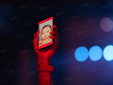 Pemain Persipura, Ruben Sanadi, mengangkat handphone dengan gambar anaknya sebelum kick off melawan Persija di Stadion Mandala, Jayapura, Papua, Jumat (29/4/2016). (Bola.com/Nicklas Hanoatubun)