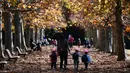 Seorang wanita bersama tiga anaknya berjalan di bawah dedaunan musim gugur ketika mereka menikmati cuaca di Gyoen Park di Tokyo (5/12/2019). Taman Nasional Shinjuku Gyoen adalah sebuah taman yang besar di area Shinjuku dan Shibuya, Tokyo, Jepang. (AFP/Charly Triballeau)