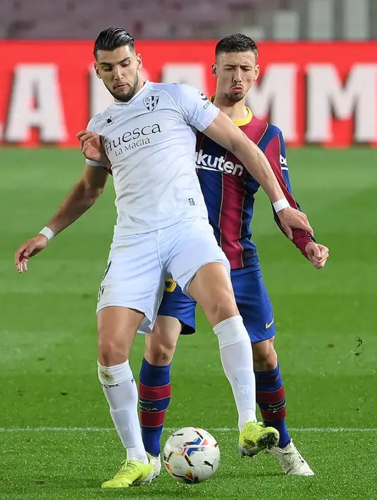 Pemain Barcelona Clement Lenglet (belakang) memperebutkan bola dengan pemain Huesca Rafa Mir pada pertandingan Liga Spanyol di Stadion Camp Nou, Barcelona, Spanyol, Senin (15/3/2021). Barcelona menang 4-1. (LLUIS GENE/AFP)