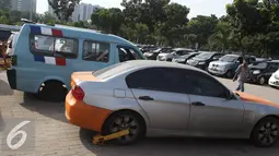 Kendaraan hasil derek karena pelanggaran yang digembok bannya terparkir di kawasan Monas, Jakarta, Selasa (3/1). Untuk mengatasi kemacetan lalu lintas, Dihubtrans DKI akan terus melakukan razia parkir liar. (Liputan6.com/Immanuel Antonius)