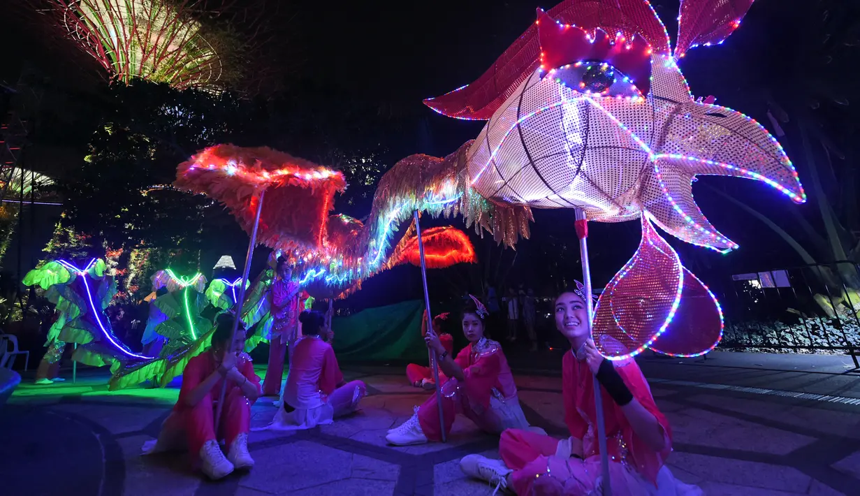 Sejumlah wanita membawakan tarian phoenix yang dihiasi dengan lampu warna-warni di Gardens by the Bay, Singapura (4/2). Pertunjukan ini digelar untuk mengantar Tahun Baru Imlek di Singapura. (AFP/Roslan Rahman)
