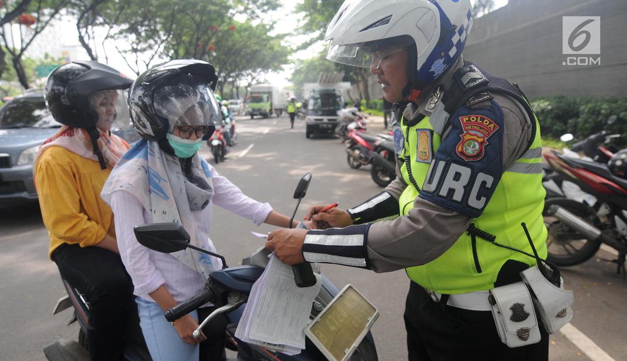 Anggota Satlantas Polres Tangerang Selatan memeriksa kelengkapan surat saat razia pajak kendaraan di Jalan BSD, Tangerang Selatan, Kamis (24/1). Razia juga untuk meningkatkan tertib lalu lintas dan disiplin pengendara bermotor. (Merdeka.com/Arie Basuki)