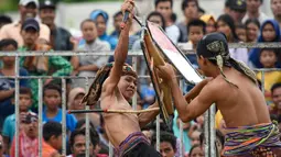 Dua pepadu (petarung) melakukan duel dalam kesenian tradisional peresean di Praya, Lombok Tengah, Selasa (19/2). Peresean merupakan festival adu ketangkasan dan kekuatan antara pemuda di kalangan suku Sasak Lombok. (MOH EL SASAKY/AFP)