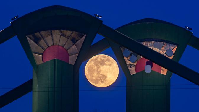 Fenomena super snow moon terlihat di antara Jembatan Floesser, Frankfurt, Jerman, Selasa (19/2). Super snow moon membuat langit berada di paras paling terang sepanjang tahun. (Frank Rumpenhorst/dpa via AP)