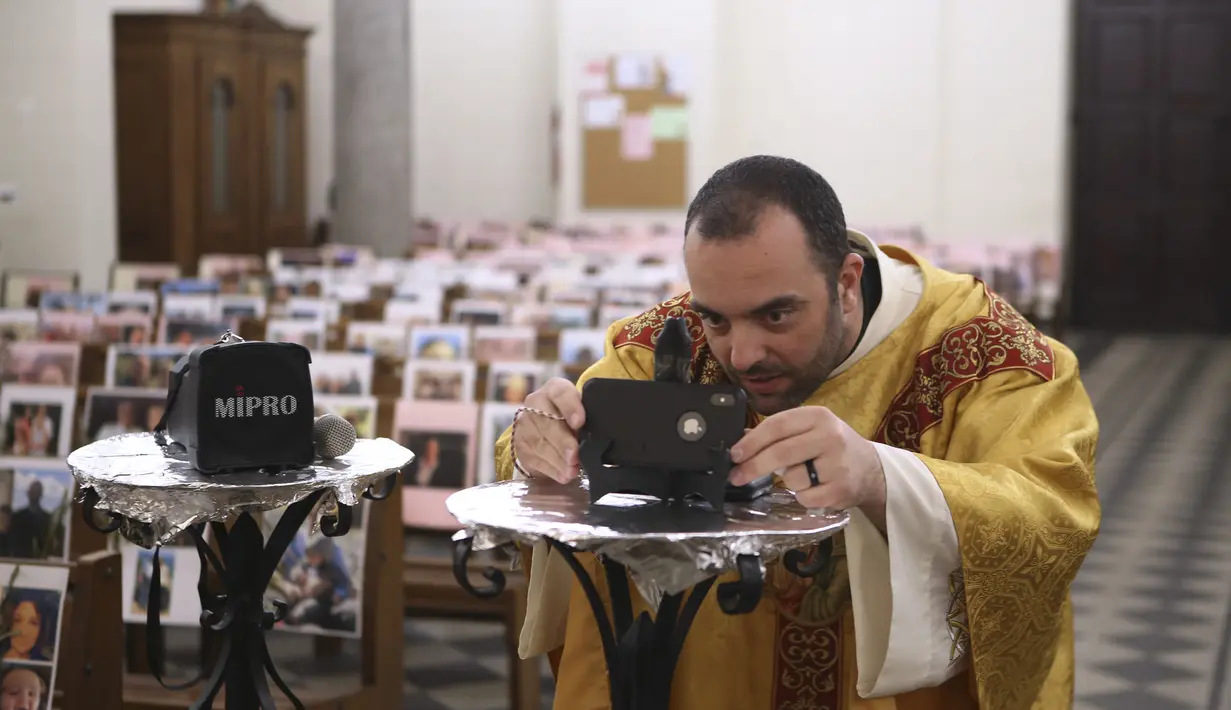 Pastor Katolik Georges Nicoli menyiapkan ponsel sebelum merayakan misa Kamis Putih yang  disiarkan langsung di Facebook di gereja Notre Dame De Lourdes di Bastia, di pulau Korsika Mediterania, Prancis (9/4/2020). (AFP/Pascal Pochard-Casabianca)