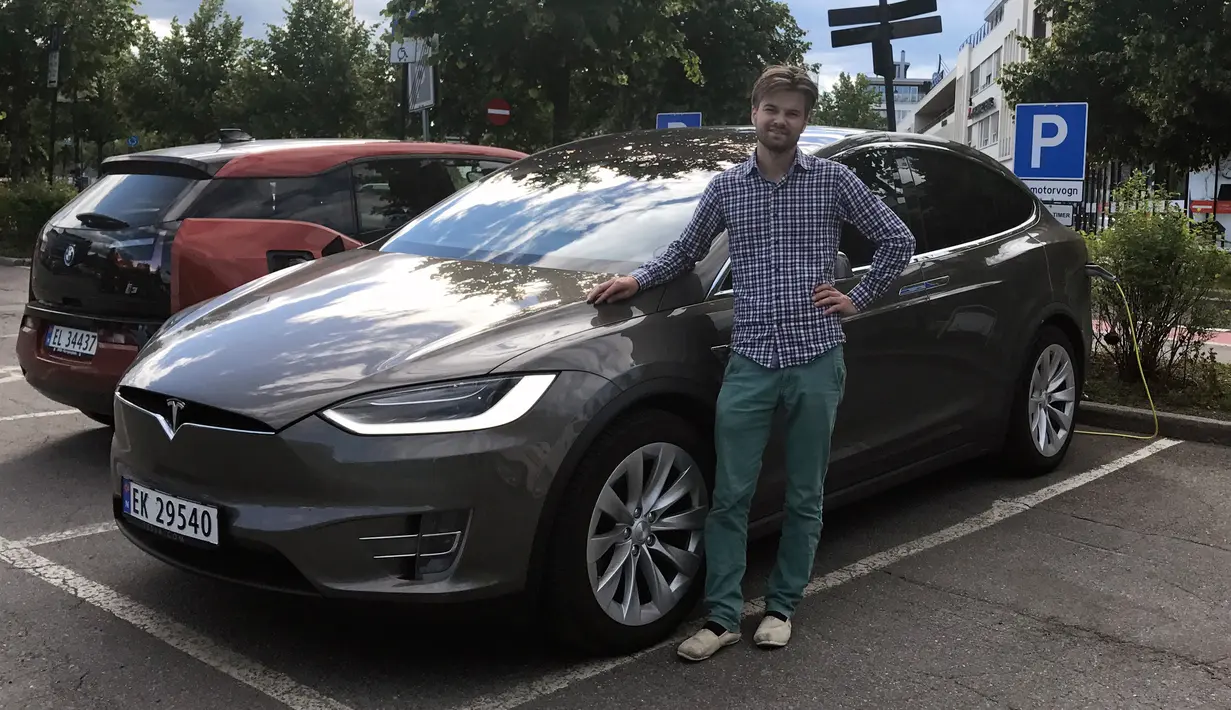 Nils Henningstad berpose di samping mobil Tesla Model X saat mengemudikan mobil listrik di stasiun pengisian umum di Oslo, Norwegia (13/07/2017). Momentum membangun mobil listrik dinilai tepat, (Lene Marie Brynildsen / Courtesy of Nils Henningstad via AP)