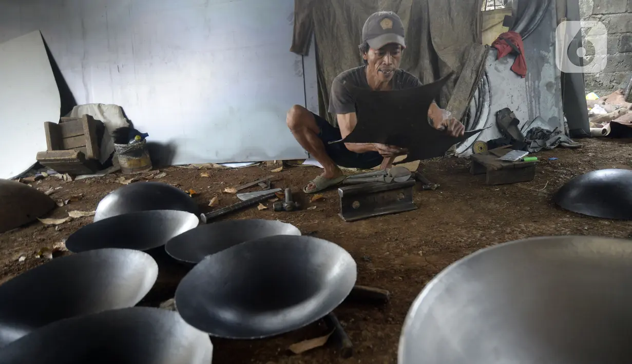 Perajin menyelesaikan pembuatan wajan yang terbuat dari pelat besi di Desa Cibadak, Tanah Sareal, Kabupaten Bogor, Jawa Barat, Rabu (5/8/2020). Pemerintah akan memberi bantuan Rp 2,4 juta dan kredit bunga rendah kepada UMKM untuk membantu pemulihan ekonomi nasional. (merdeka.com/Dwi Narwoko)