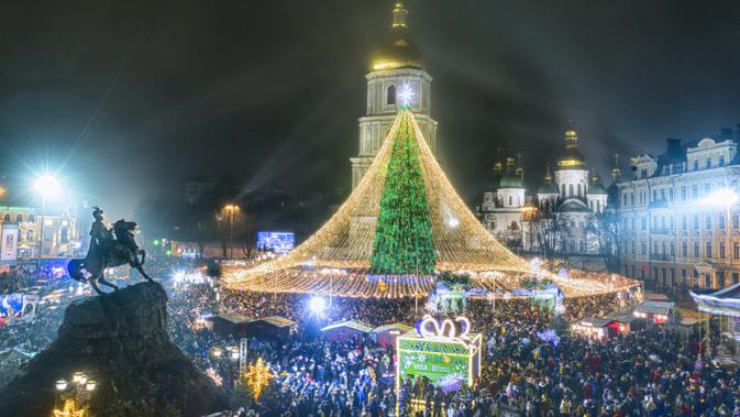 Kerumunan orang merayakan Tahun Baru di sekitar pohon Natal dengan Katedral St. Sofia sebagai latar belakang di Kyiv, Ukraina, Jumat pagi, 1 Januari 2021. Terlepas dari pembatasan karantina COVID-19, banyak orang Ukraina menikmati Tahun Baru di luar ruangan acara. (AP Photo/Efrem Lukatsky)