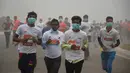 Peserta lari New Delhi 10K menggunakan masker tetap mengikuti lomba ditengah-tengah kabut polusi yang menimpa kota New Delhi, India (6/11). Kabut asap ini diklaim sebagai kabut terparah yang dialami oleh New Delhi dalam 17 tahun. (AFP/Dominique Faget)