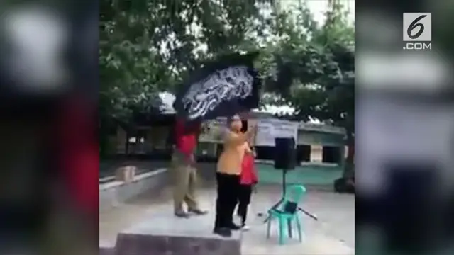 Rekaman video anak murid sekolah dasar mengibarkan bendera hitam bertuliskan huruf Arab.