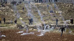 Demonstran Palestina lari dari gas air mata yang ditembakkan oleh pasukan Israel selama protes terhadap permukiman Israel, di desa Deir Jarir Tepi Barat, utara Ramallah, Jumat (1/1/2021). (AP Photo/Majdi Mohammed)