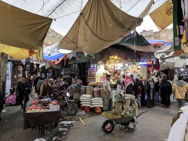 Orang-orang berbelanja buah-buahan dan kacang-kacangan kering di pasar terbuka di ibu kota Yaman, Sanaa (2/5/2021). Umat Muslim di Yaman memenuhi pasar menjelang liburan Idul Fitri yang menandai akhir bulan suci Ramadhan. (AFP/Mohammed Huwais)
