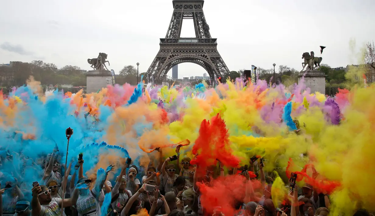 Pemandangan ketika sejumlah orang melempar bubuk berwarna saat merayakan akhir perlombaan Color Run 2018 dengan latar belakang Menara Eiffel di Paris, Prancis (15/4). (AP/Thibault Camus)