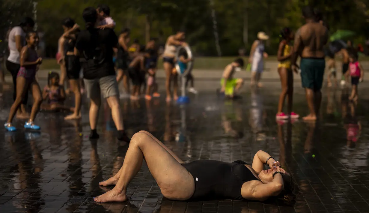 Orang-orang bersantai di pantai perkotaan di taman Madrid Rio di Madrid, Spanyol, Rabu (13/7/2022). Para pakar meteorologi mengatakan massa udara yang terlalu panas dan angin hangat dari Afrika mendorong suhu di kawasan Semenanjung Iberia naik melebihi suhu biasanya. (AP Photo/Manu Fernandez)