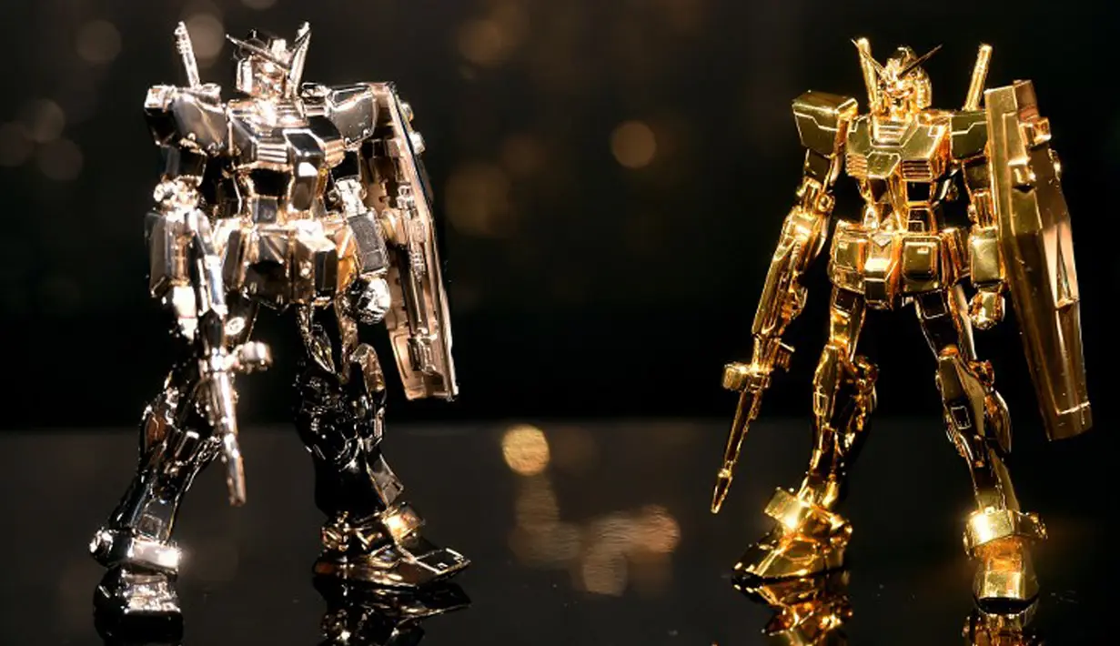 Robot Gundam yang terbuat dari emas (kanan) disejajarkan dengan robot Gundam yang terbuat dari perak dalam acara pameran "The Art of Gundam" di Tokyo, 17 Juli 2015. Pameran tersebut berlangsung dari 18 Juli-27 September 2015. (AFP PHOTO/Yoshikazu Tsuno)