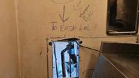 Celah di belakang toilet di dalam sel tempat para napi melarikan diri — lengkap dengan pesan ejekan yang ditulis di dinding dengan tulisan "Terlalu Gampang LoL" dengan tanda panah yang menunjuk ke celah tersebut. (AP)