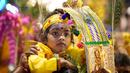 Umat Hindu membawa kanopi berhias yang disebut "kavadi" dan anak-anak berjalan menuju Kuil Swamy Sri Subramaniar pada perayaan Thaipusam di Batu Caves, Kuala Lumpur, Malaysia, Minggu (5/2/2023). Thaipusam, yang dirayakan untuk menghormati Dewa Murugan, adalah acara tahunan umat Hindu untuk mencari berkah, memenuhi sumpah, dan mengucapkan terima kasih. (AP Photo/Vincent Thian)