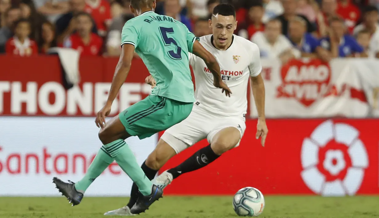 Pemain Sevilla, Lucas Ocampos berusaha melewati bek Real Madrid, Raphael Varane selama pertandingan lanjutan La Liga Spanyol di stadion Ramon Sanchez Pizjuan di Seville (22/9/2019). Real Madrid menang tipis atas Sevilla 1-0. (AP Photo/Miguel Morenatti)