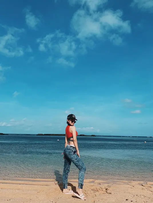Main di pantai dengan gaya? Siapa takut? Michelle tampak mengenakan crop top merah, dipadunya dengan pilihan sederhana, yaitu celana jeans, dan sandal putih. Ia juga tampak mengenakan topi hitam dan sunglasses. Foto: Instagram.