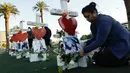 Cece Navarrette meletakkan bunga di sebuah nisan milik saudaranya, Bailey Schweitzer yang menjadi korban penembakan massal di Las Vegas, Jumat (6/10). Sebanyak 58 nisan kayu berbentuk salib itu ditambahkan ornamen hati berwarna merah. (AP/Gregory Bull)