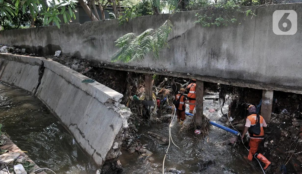 Petugas PPSU melintasi tembok jebol akibat derasnya arus banjir rob di Kompleks Perumahan Pantai Mutiara, Pluit, Jakarta, Minggu (7/6/2020). (merdeka.com/Iqbal S. Nugroho)
