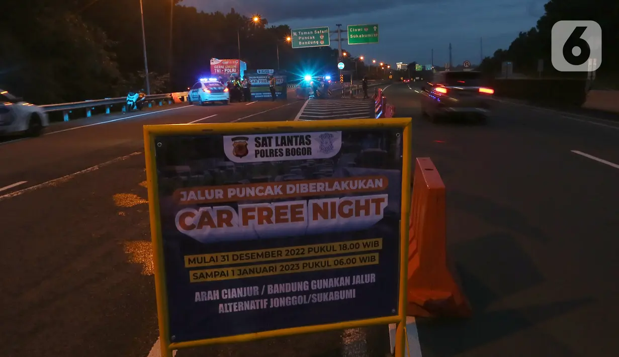 Petugas dari Polres Bogor memasang rambu penutupan jalan di pintu keluar Tol Gadog, Bogor, Sabtu (31/12/2022). Penutupan jalan jalur Puncak Bogor untuk gelaran Car Free Night dimulai sejak pukul 18.00 WIBdan dibuka kembali esok pagi pukul 06.00 WIB. (merdeka.com/Arie Basuki)