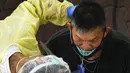 Seorang petugas kesehatan mengumpulkan sampel usap (swab) untuk pengujian COVID-19 dari para pekerja yang siap kembali bekerja di pusat penapisan (screening) regional di Singapura (10/6/2020). (Xinhua/Then Chih Wey)