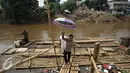 Warga usai menyebrangi Kali Ciliwung mengunakan eretan, Jakarta, Senin (30/11). Tidak adanya fasilitas jembatan menyebabkan warga memilih eretan sebagai sarana penyeberangan sehari-hari, meskipun dengan kondisi seadanya. (Liputan6.com/Immnuel Antonius)