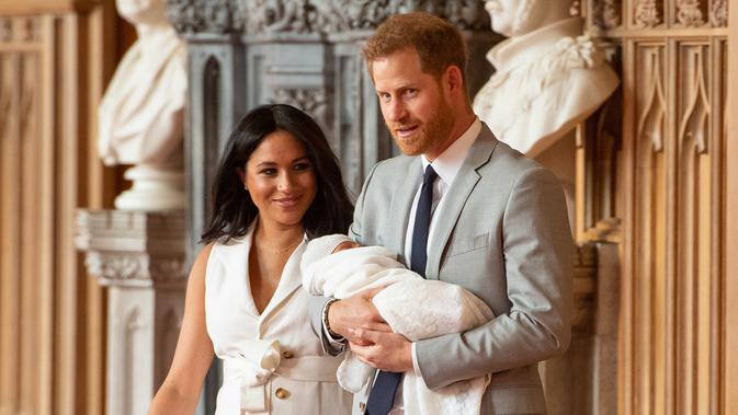 Pangeran Harry dan Meghan Markle berjalan membawa bayi laki-lakinya yang baru lahir di St George's Hall di Windsor Castle di Windsor, London (8/5/2019). Pangeran Harry menyatakan bahwa dia dan Meghan Markle masih memikirkan nama anak mereka. (AFP Photo/Dominic Lipinski)