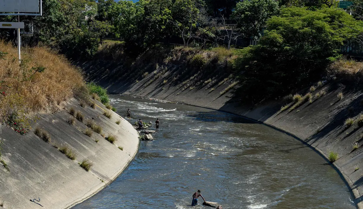 Sejumlah pria mencari logam berharga di Sungai Guaire, di Caracas, Venezuela (1/2). Puluhan warga mencari logam atau tembaga setiap hari di Sungai Guaire, tempat selokan Caracas mengalir.  (AFP Photo/Federico Parra)