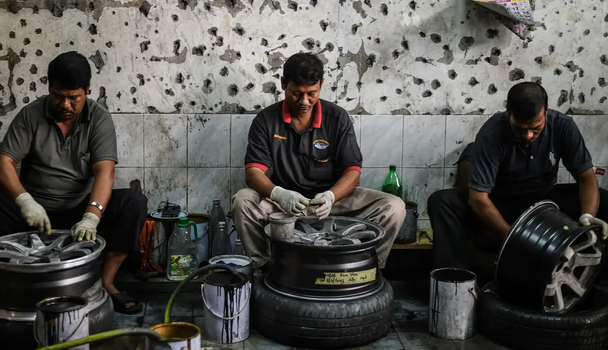 Para pekerja mencuci pelek mobil bekas sebelum menyemprotnya dengan cat di sebuah bengkel di Ampang, di pinggiran kota Kuala Lumpur, Malaysia (18/7). (AFP Photo/Mohd Rasfan)