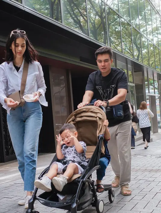 Memegang mangkok kecil dan tangan kanannya siap memberikan suapan untuk putra keduanya, Kenzo. Sedangkan sang suami, Baim Wong mendorong stroller yang berisi dua anaknya. [Instagram/paula_verhoeven]