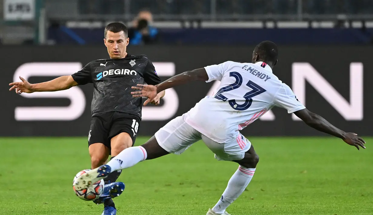 Bek Real Madrid, Ferland Mendy berusaha merebut bola dari pemain Borussia Monchengladbach, Stefan Lainer pada pertandingan grup B Liga Champions di  Borussia Park, Jerman, Selasa (27/10/2020). Madrid bermain imbang 2-2 atas Monchengladbach. (AFP Photo/Ina Fassbender)
