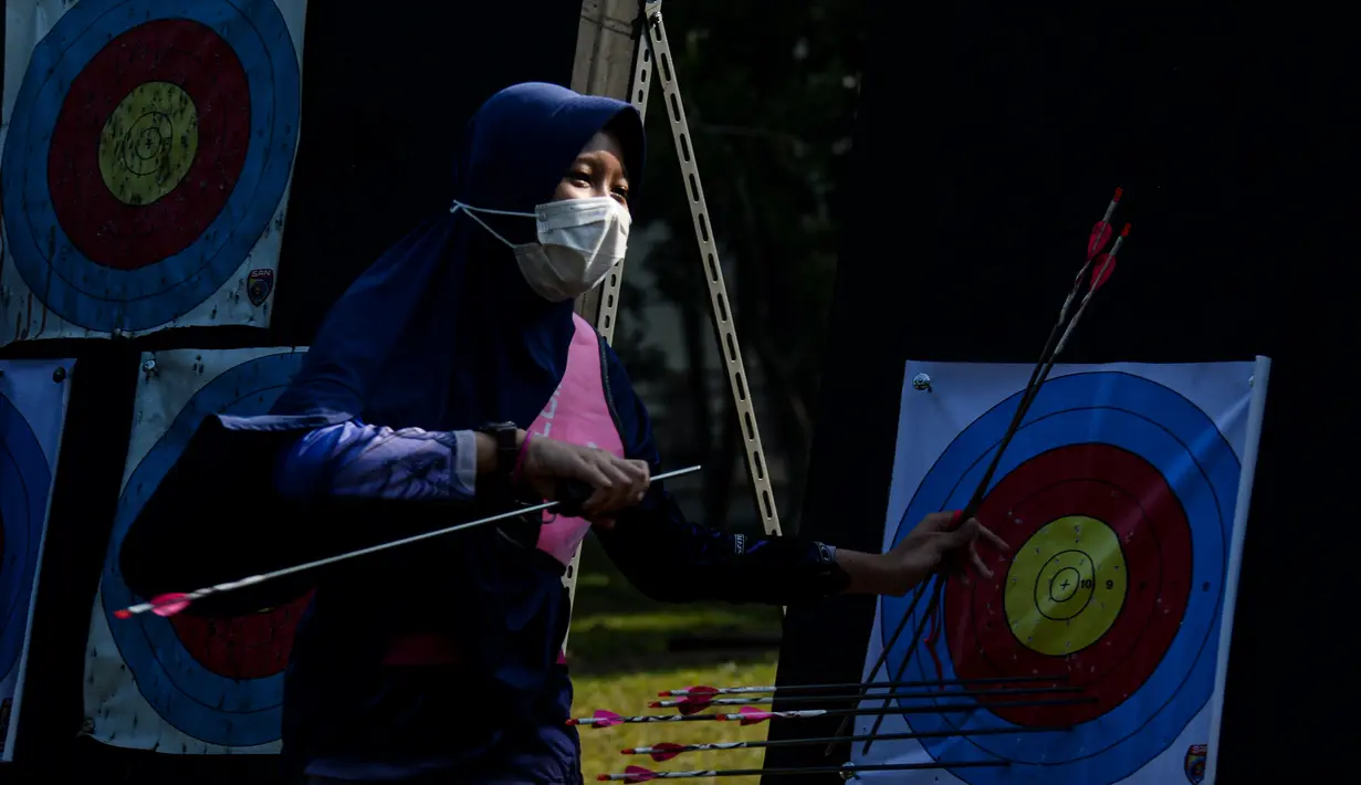 Seorang gadis memakai masker mencabut anak panah dari papan target saat latihan panahan yang diadakan oleh SAN Archery Club di Desa Ciater, Tangerang Selatan (9/8/2020).  (Agung Kuncahya B./Xinhua)