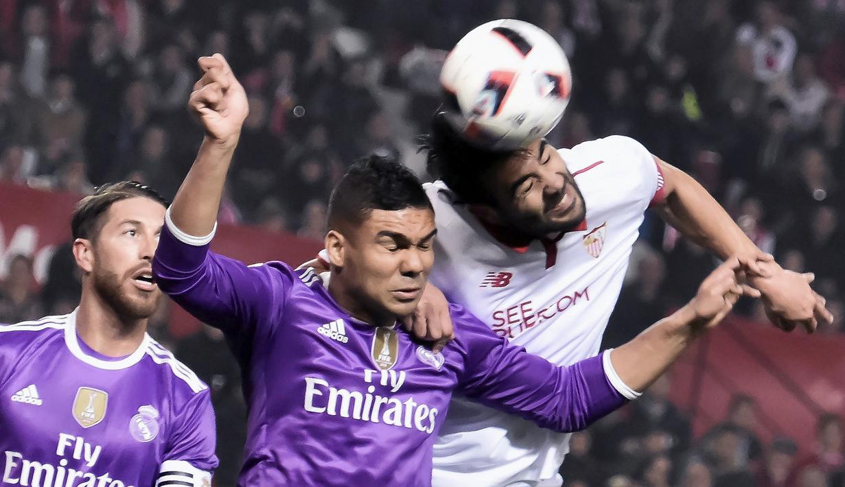 Pemain Real Madrid, Casemiro (tengah) berduel dengan pemain Sevilla, Vicente Iborra (kanan) pada laga Copa Del Rey di Ramon Sanchez Pizjuan stadium, Seville (12/1/2017). real Madird bermain imbang 3-3. (EPA/Raul Caro)
