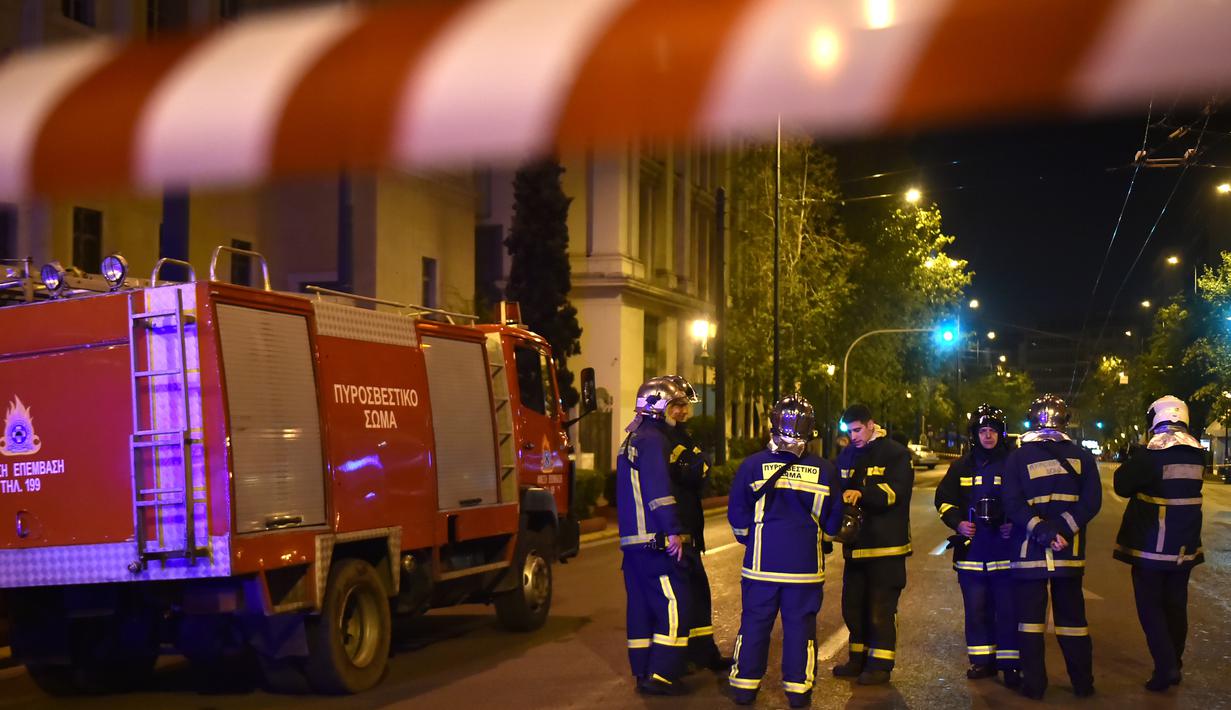 Petugas pemadam tiba di lokasi serangan bom yang menghantam sebuah kantor cabang bank asal Yunani, Eurobank, di pusat Kota Athena, Rabu (19/4). Seorang tak dikenal sempat memberi peringatan melalui telepon kepada situs Zougla. (LOUISA GOULIAMAKI/AFP)
