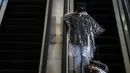 Seorang perempuan dengan jas hujan sekali pakai menaiki eskalator di Bandara Internasional Los Angeles di Los Angeles, California, 23 November 2020. Menjelang Thanksgiving, Pusat Pengendalian Penyakit mengimbau agar orang Amerika tak bepergian di tengah lonjakan Covid-19 di AS. (AP Photo/Jae C. Hong