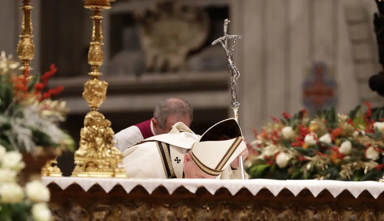 Paus Fransiskus mencium altar ketika memimpin misa Malam Natal di Basilika Santo Petrus, Vatikan, Selasa (24/12/2019). Paus Fransiskus memimpin Natal bagi 1,3 miliar umat Katolik dunia. (AP Photo/Alessandra Tarantino)